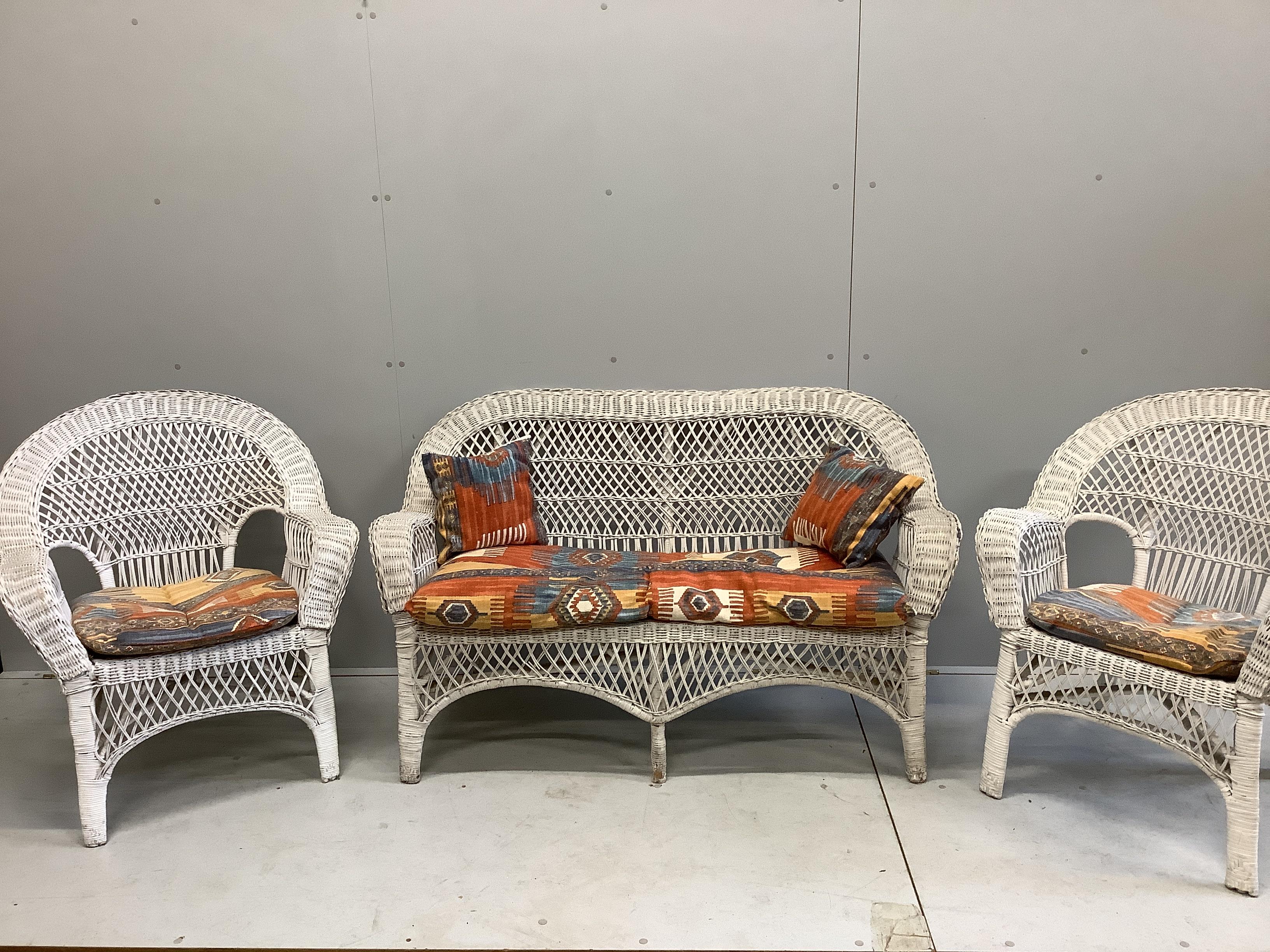 A vintage wicker three piece conservatory suite with Kilim style printed fabric cushions, settee width 134cm, depth 54cm, height 81cm